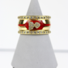 Der 750/Gelbgold-Ring wird auf einem grauen Kegelständer präsentiert, weist rote Emaille-Akzente mit schleifenförmigen Verzierungen auf und ist mit kleinen, klaren Edelsteinen von insgesamt etwa 0,9 Karat geschmückt.
