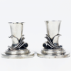 Zwei Kerzenhalter aus 925er Sterlingsilber von Georg Jensen Ag, entworfen um 1930 im Art Déco-Stil, zeigen dekorative Wirbelmuster, die nebeneinander auf einem schlichten Hintergrund stehen. Jeder Halter besteht aus einem zylindrischen oberen Teil und einem runden Sockel.