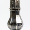 Ein alter Zuckerstreuer aus Metall, genannt „Antiker Zuckerstreuer“, wurde um 1800 aus russischem Silber mit dem Stempel 13 Lot (entspricht Silber Ag/812) gefertigt und hat einen perforierten, kuppelförmigen Deckel mit einem kunstvollen Muster. Der bauchige Körper hat eine reflektierende Oberfläche, die Anzeichen von Anlaufen zeigt, und steht elegant auf einem dekorativen Sockel.