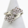 Ein 585er Weißgoldring, der mit zehn Diamanten im Brillantschliff verziert ist, die in einem kaskadenförmigen Design angeordnet sind. Das glänzende Metallband hebt sich von einem sanft verschwommenen Hintergrund ab.