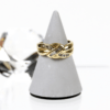 Der mit acht Brillanten von insgesamt etwa 0,16 Karat und sieben Baguette-Diamanten von etwa 0,09 Karat besetzte 585/Gelbgold-Ring wird auf einem grauen, kegelförmigen Ständer präsentiert, vor dem Hintergrund eines facettierten Kristallobjekts.