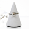Der 750/Weißgold/Bicolor-Ring mit einem massiven runden Diamanten von ca. 0,65 Karat mit der Reinheit Si-P und der Farbe I-J wird auf einem grauen, kegelförmigen Ständer vor weißem Hintergrund präsentiert.