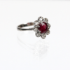 Ein 585/Weißgold-Ring mit einem zentralen Rubin, umgeben von acht kleinen Diamanten, die sich vor einem weißen Hintergrund abheben.