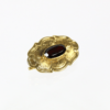 Produktbeschreibung: Die 585/Antike Gelbgold Brosche mit Granat ist eine elegante Goldbrosche, die in der Mitte mit einem ovalen dunkelroten Edelstein verziert ist und aufwendige Details auf der Goldoberfläche aufweist. Sie wird auf einem glatten weißen Hintergrund präsentiert, was für einen beeindruckenden visuellen Effekt sorgt.