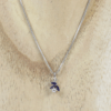 Eine 585/Weißgold-Kette mit Verlängerungs- und Zwischenöse, geschmückt mit einem Anhänger mit zwei dunkelblauen Steinen und einem weißen Mittelstein von ca. 0,08 Karat, präsentiert auf einer Holzunterlage.