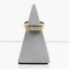 Ein 750er Gelbgoldring mit vier Brillanten von insgesamt etwa 0,49 Karat wird auf einem grauen, dreieckigen Ständer vor weißem Hintergrund präsentiert.