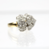 Ein 585/Bicolor-Ring, der mit 35 brillanten Diamanten mit einem Gesamtgewicht von ca. 0,95 Karat und der Reinheit Si2-P1/I verziert ist, weist ein Doppelcluster-Design auf. Die Cluster sind symmetrisch angeordnet, um ein elegantes florales Erscheinungsbild zu erzeugen, das wunderschön auf einer reflektierenden weißen Oberfläche ruht.
