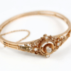Ein 585/Roségold-Armband aus der Art Déco-Kollektion, das mittig ein verziertes Kreismotiv aufweist, das mit einem Altschliff-Diamanten von ca. 0,25 Karat und vier Perlen geschmückt ist. Für mehr Sicherheit ist das Armband mit einer Sicherheitskette ausgestattet.