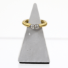 Ein 750/Gelbgold-Ring mit zwei runden Brillanten von insgesamt ca. 0,35 Karat, Reinheit Si/I-J, wird auf einem grauen dreieckigen Ständer vor weißem Hintergrund präsentiert.