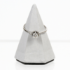Ein 750er Weißgoldring mit einem Solitärdiamanten von ca. 0,24 ct. Vs/H sitzt auf einem kleinen, grauen, kegelförmigen Sockel vor einem schlichten weißen Hintergrund.
