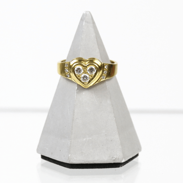 Der 750/Ring mit Brillanten zus. ca. 0,4ct. Vs-Si/G (Top Wesselton), ein Goldring mit herzförmigem Design und eingefassten Edelsteinen, wird elegant auf einem grauen, pyramidenförmigen Ständer präsentiert.