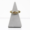 Auf einem grauen, kegelförmigen Ständer vor weißem Hintergrund präsentiert sich ein 750/Gelbgold-Ring, der mit drei kleinen Brillanten von insgesamt etwa 0,06 Karat verziert ist.