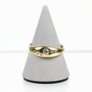 Ein Goldring mit einem eleganten, geschwungenen Design wird auf einem grauen Kegelständer präsentiert. Der Ring mit der Bezeichnung 585/Gelbgold Ring mit Brillanten verfügt über einen zentralen runden Diamanten mit einem Gewicht von etwa 0,10 Karat, der auf beiden Seiten durch kleinere Diamanten mit einem Gesamtgewicht von etwa 0,15 Karat hervorgehoben wird.