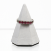 Ein 585/Weißgold-Ring mit fünf Rubinen wird auf einem kleinen, grauen Pyramidenständer vor einem schlichten weißen Hintergrund präsentiert.